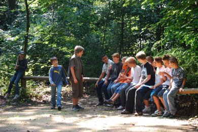 Eine Gruppe von Jugendlichen sitzt auf einem Holzgeländer im Wald