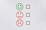 Drei verschieden zufriedene Smilies zum Ankreuzen auf einem Blatt Papier