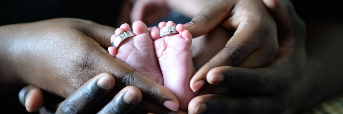 Zwei Personen umfassen die Füße eines Babys