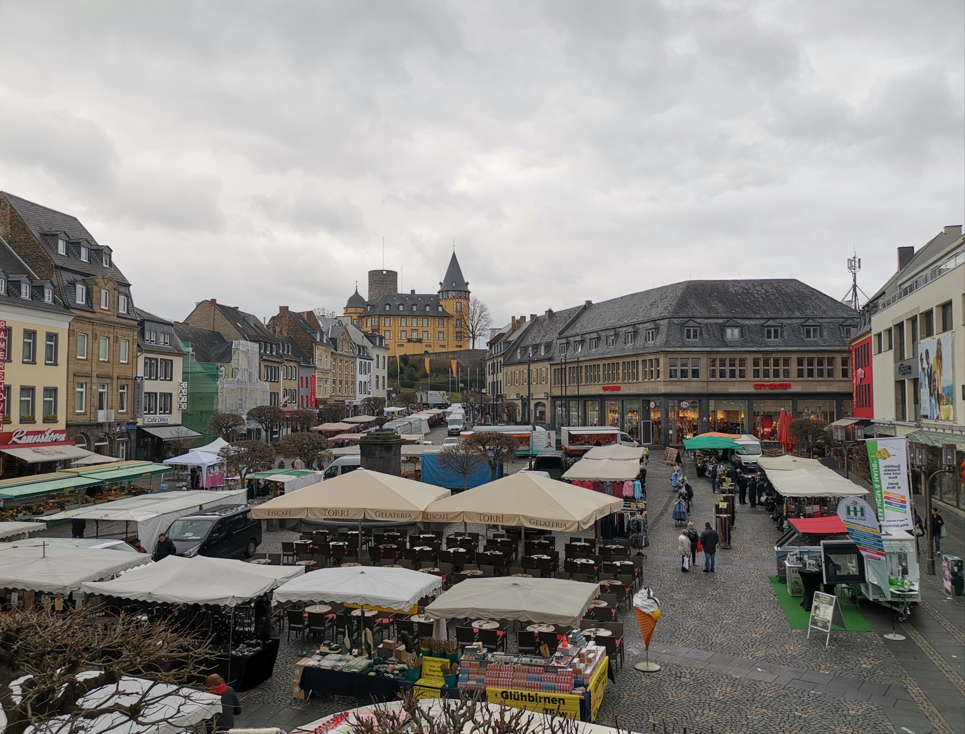 Blick auf den Marktplatz mit Marktständen und der Genovevaburg im Hintergrund