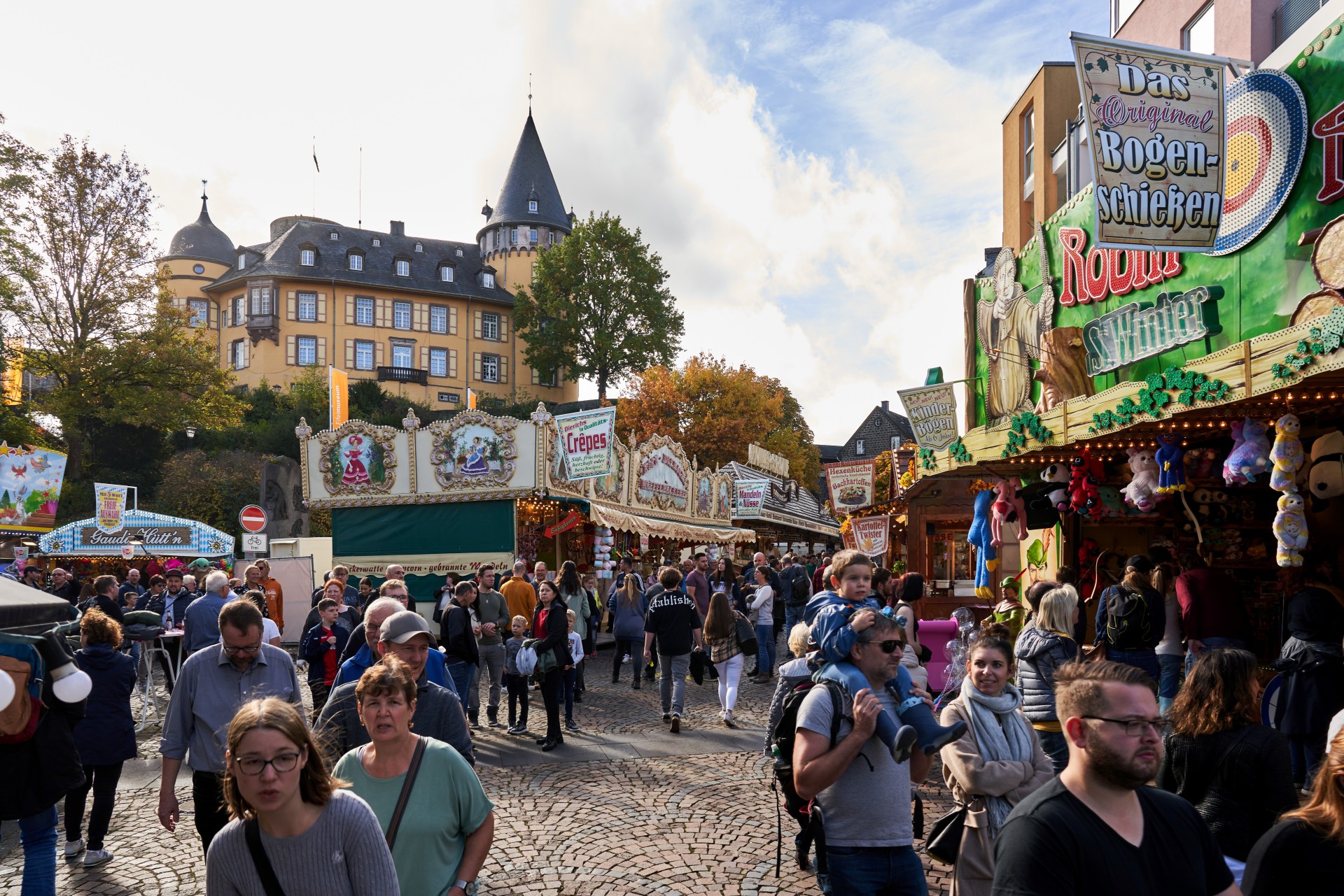 Menschen auf dem Lukasmarkt mit Genovevaburg im Hintergrund