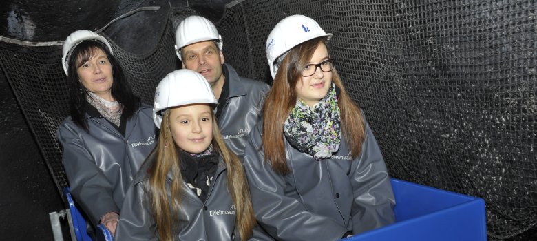 Virtuelle Lorenfahrt Zwei Mädchen sitzen mit ihren Eltern in einer blauen Lore und erleben die virtuelle Lorenfahrt