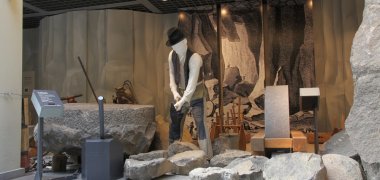 Einblick in die Ausstellungshalle Steinzeiten, man sieht die Figur eines Steinarbeiters bei der Arbeit.