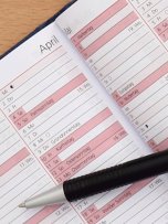 Auf einem aufgeschlagenen Kalender liegt ein schwarzer Kugelschreiber.