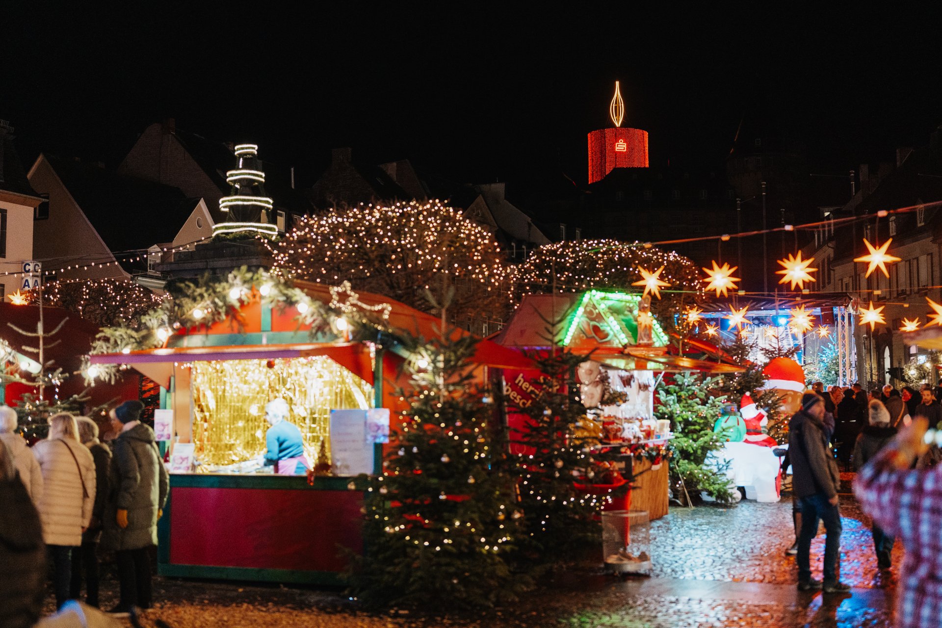 Lichter Leuchten auf dem Weihnachtsmarkt mit Blick auf die leuchtende Genovevaburg