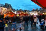 Menschen, die über den Weihnachtsmarkt mit seinen roten Verkaufshäuschen schlendern
