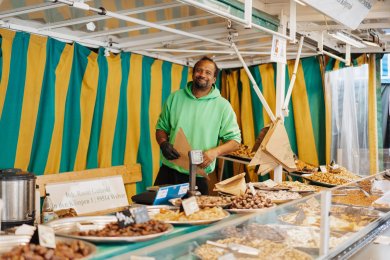 Krammarkt Person steht hinter einem Marktstand mit gebrannten Mandeln