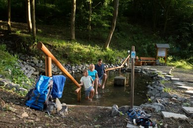 Natur-Kneipp-Becken Eine Familie erfrischt ihre Füße im Wasser der Natur-Kneippanlage. Diese ist an einem Wanderweg.