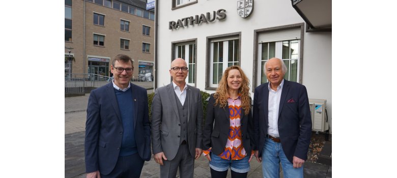 4 Personen stehen vor dem Rathaus für ein Foto zusammen