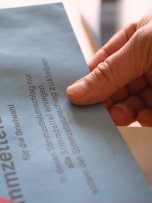 Hände mit Briefwahlunterlagen