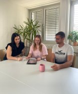 2 Frauen und ein Mann sitzen an einem Tisch und recherchieren