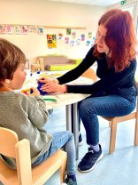 Erzieherin mit einem Kind zusammen beim Knete spielen in der Kindertagesstätte