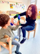 Erzieherin mit einem Kind zusammen beim Knete spielen in der Kindertagesstätte