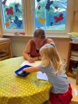 Teilzeitausbildung zum/zur staatlich anerkannten Erzieher/in Erzieherin sitzt mit einem Kind an einem Tisch und malt