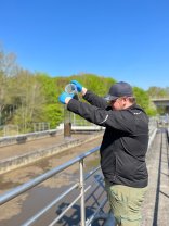 Ein Mann nimmt Boden- und Wasserproben mit zwei Messbechern