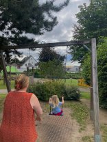 Erzieherin schubst Kind auf einer Schaukel an