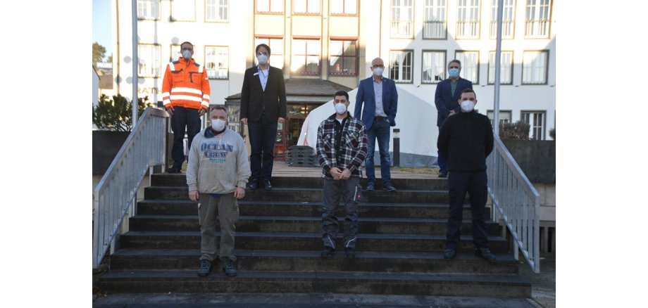 7 Personen stehen mit Abstand zueinander und mit Mund-Nasen-Schutz  auf der Treppe vor dem Rathaus 