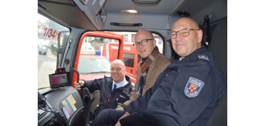 Oberbürgermeister Dirk Meid, Wehrleiter Andreas Faber und Uli Walsdorf sitzen im Feuerwehrwagen