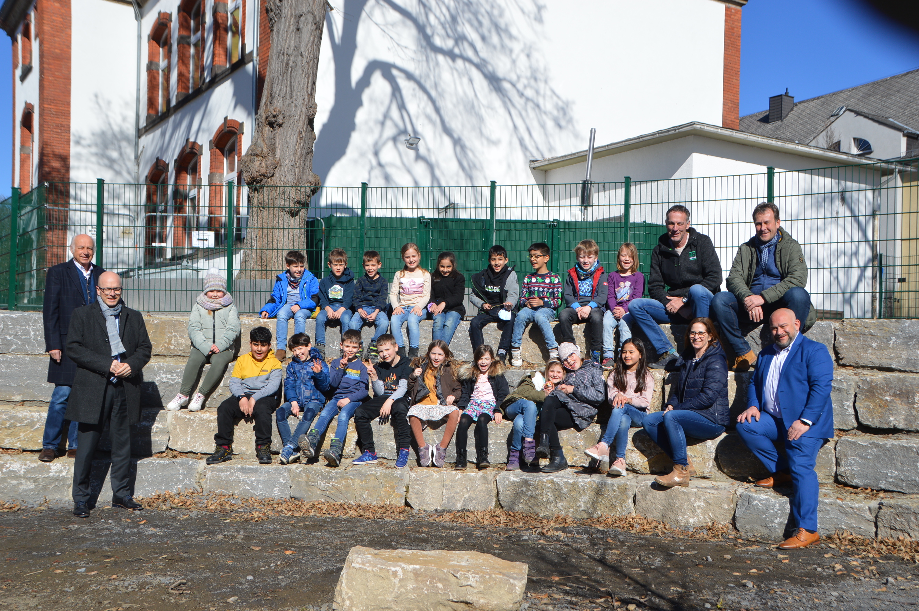 Bürgermeister Bernhard Mauel, Oberbürgermeister Dirk Meid, Bernd May von der bauausführenden Firma Schulz, Norbert May vom Bereich Tiefbau, stellvertretende Schulleiterin Anke Guckenbiehl, Schulleiter Stefan Ostrominski und eine Schulklasse probieren das neue wassernahe Klassenzimmer aus