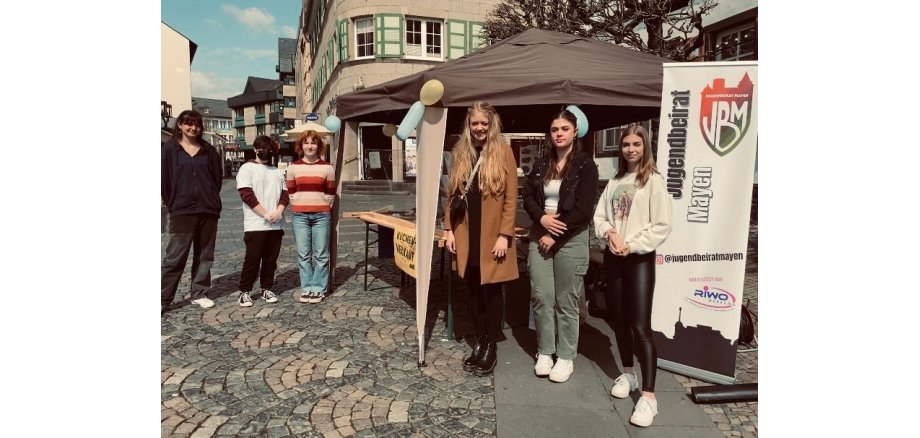 6 Personen vor einem Verkaufsstand auf dem Mayener Marktplatz