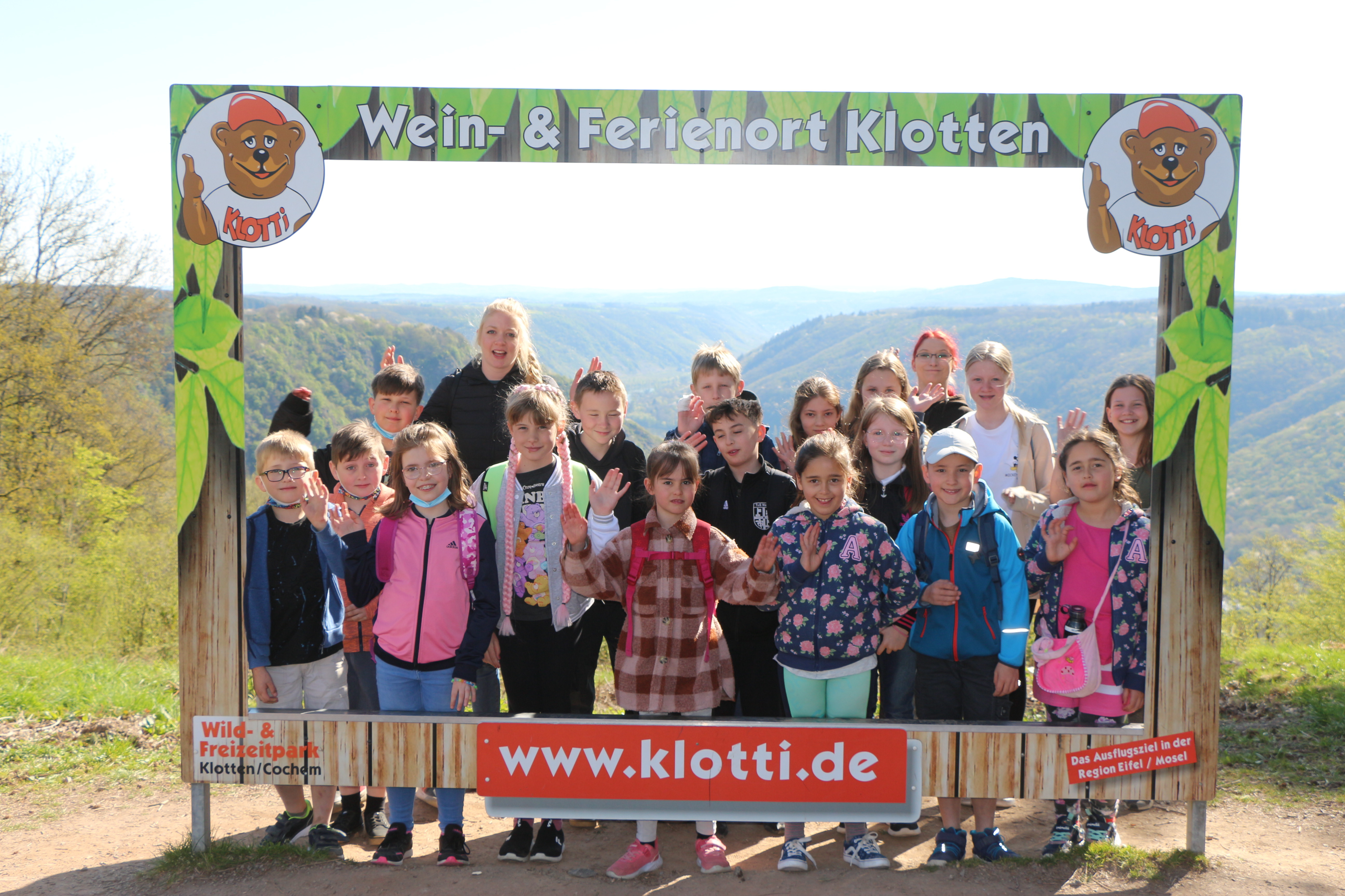 Auf dem Bild ist eine Gruppe Kinder mit Betreuern hinter einem Fotopanorama vom Ferienort Klotten zu sehen