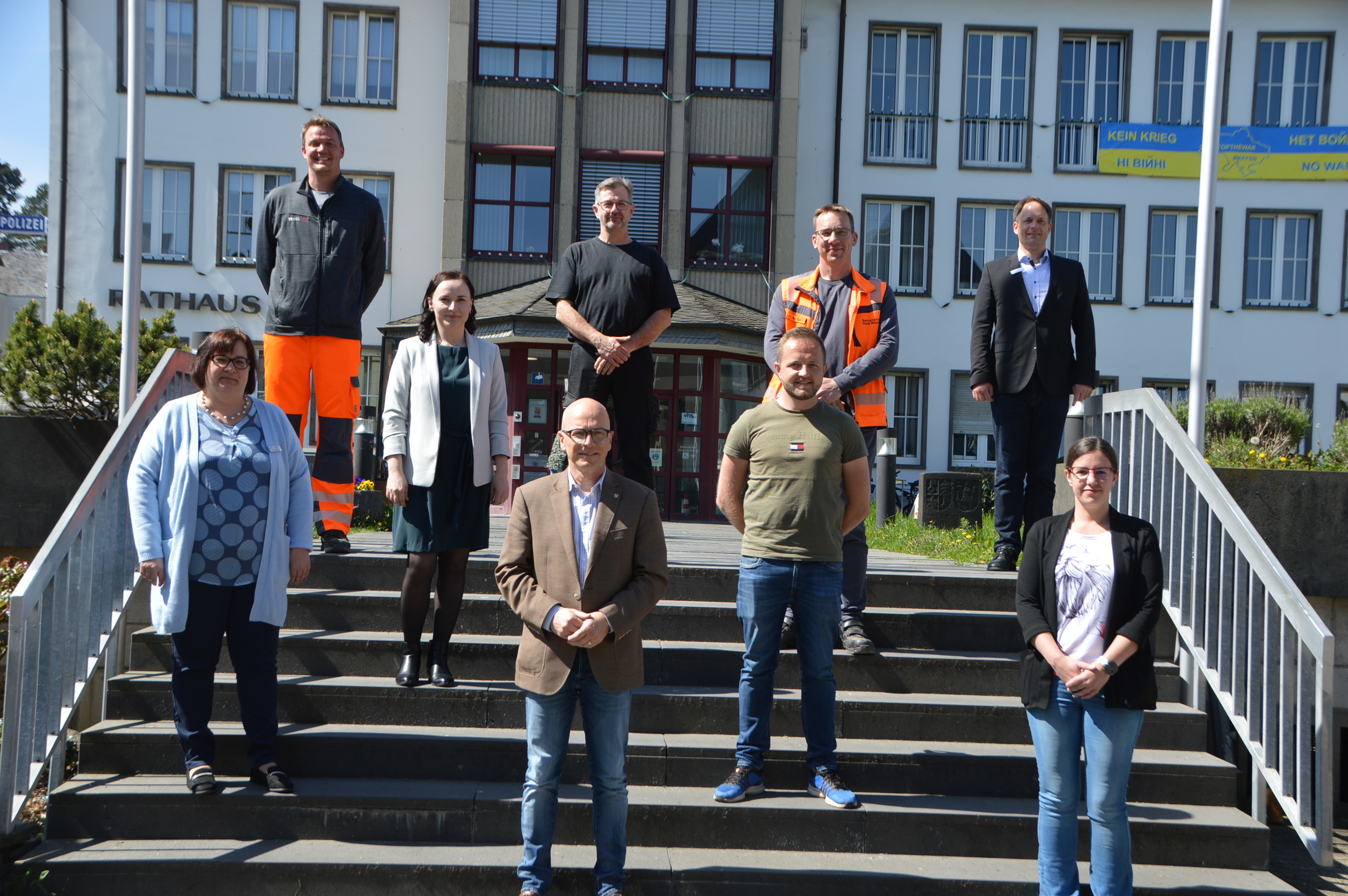 9 Personen stehen auf der Treppen vor dem Mayener Rathaus
