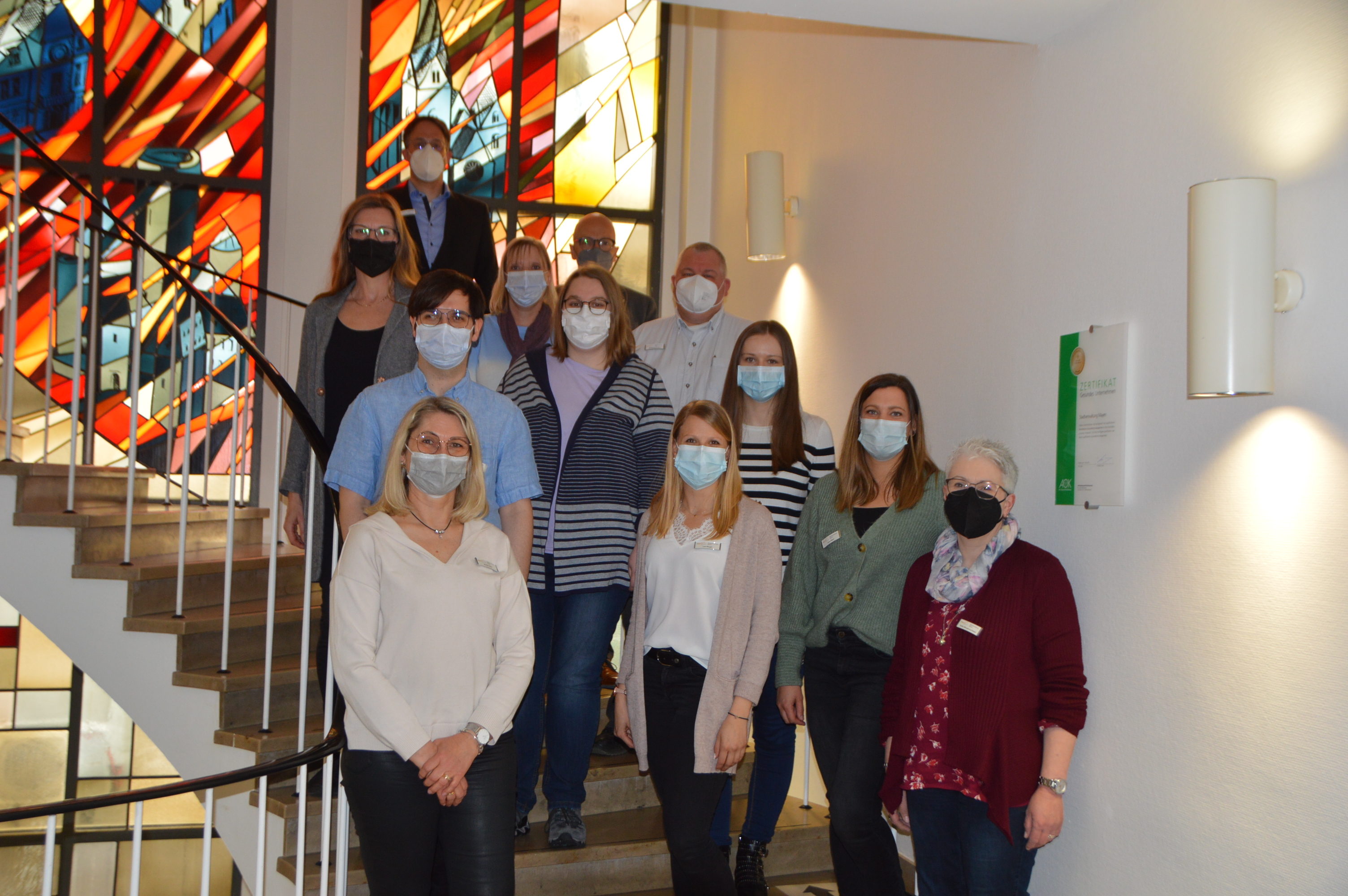 von links nach rechts: Beate Oster, Tommy Elm, Dagmar Breitova, Büroleiter Christoph Buttner, Birgit Holthaus, Oberbürgermeister Dirk Meid, Lisa Hörter, Personalratsvorsitzender Wolfgang Goeken, Lea Ringel, Katrin Laktujuschin, Lena Rech und Heike Morgenschweis auf der Treppe des Rathauses