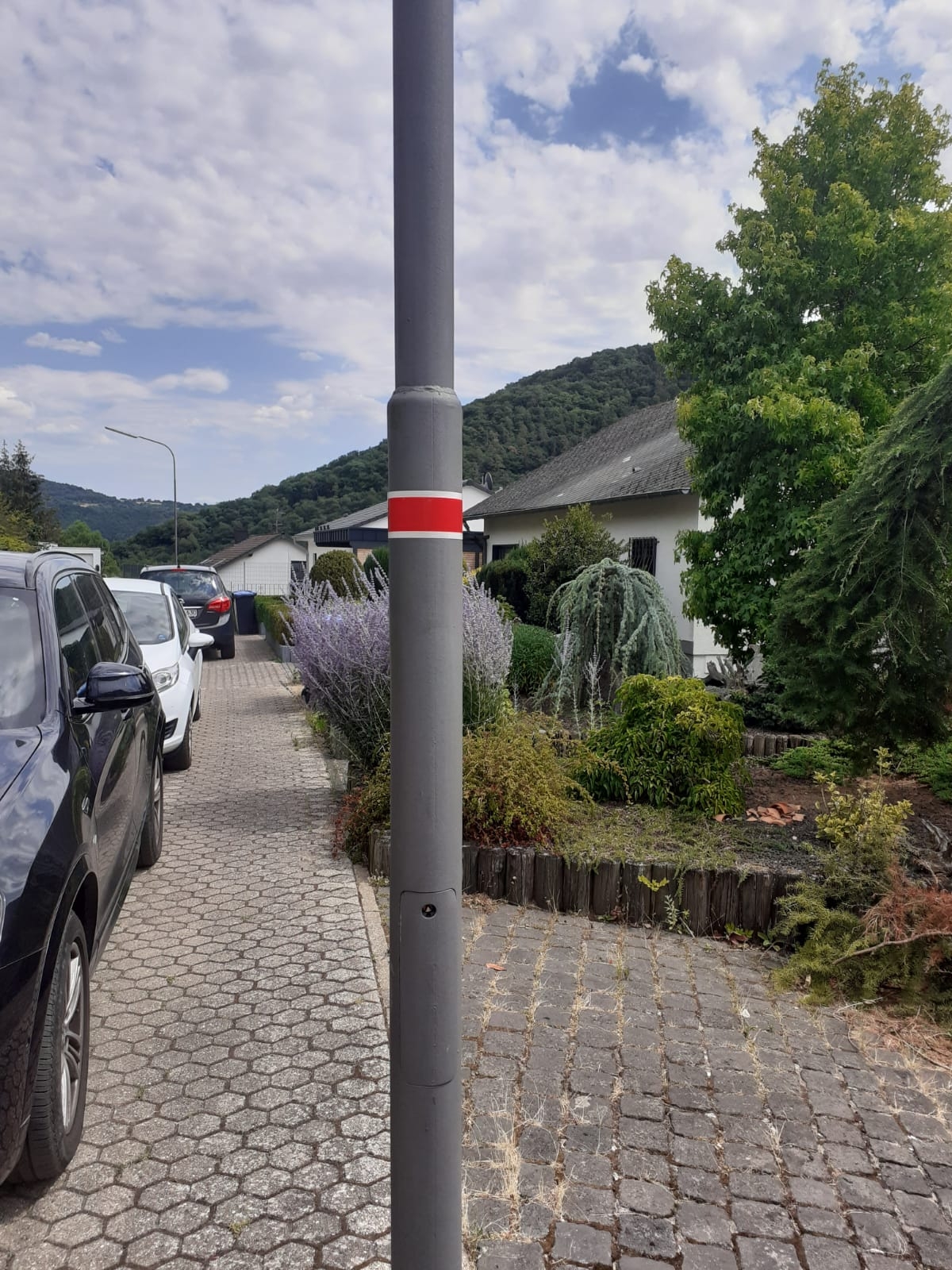 Man sieht eine Straßenlaterne in einem Wohngebiet mit der Aufkleber, welche rot und weiß ist