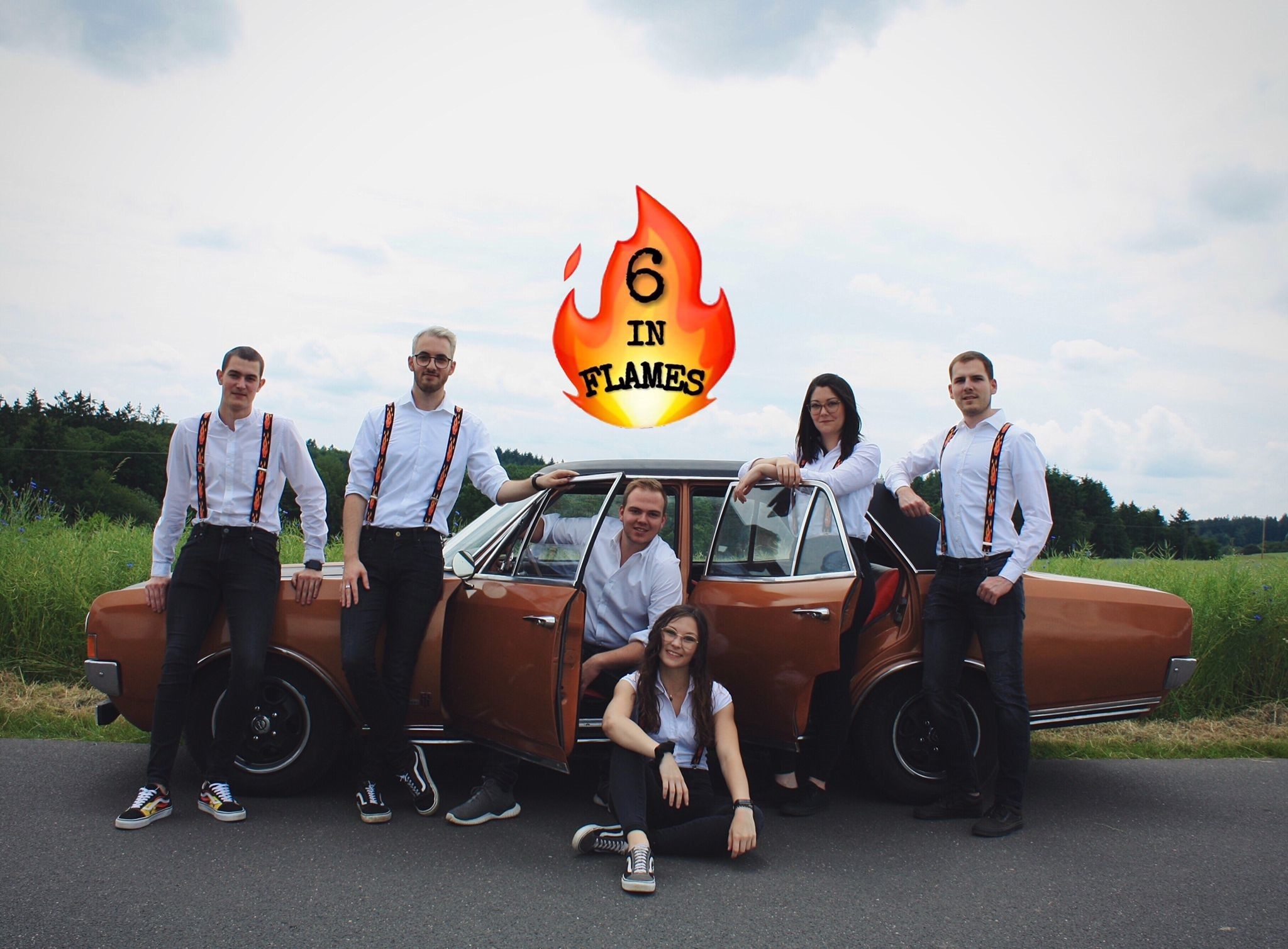 Sechs Personen stehen an einem Auto. Weißes Oberteil und schwarze Hose. Darüber das Logo der Band