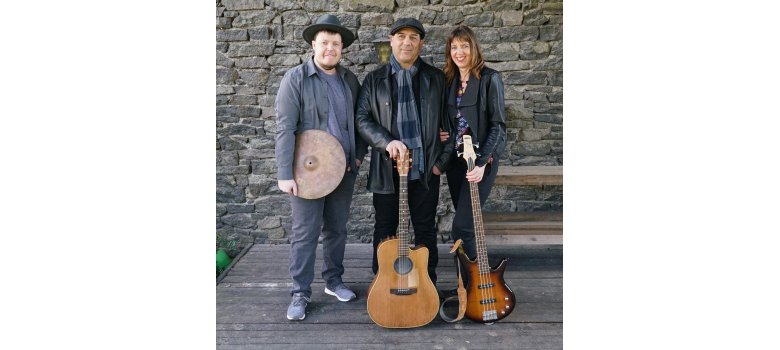 Drei Personen mit Instrumenten stehen vor einer Steinwand