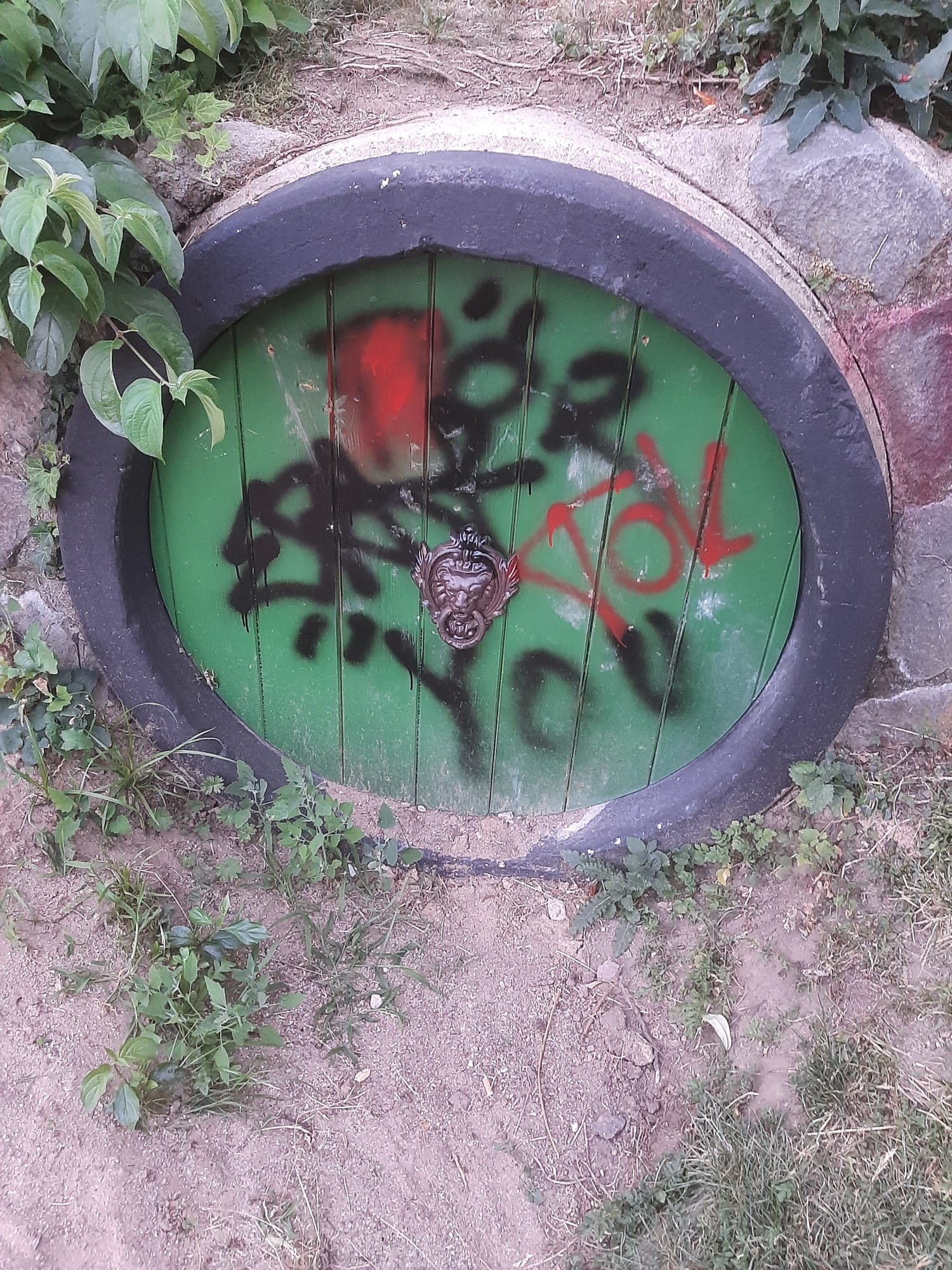 Der Eingang eines Kriechrohres ist mit rotem und schwarzem Graffiti besprüht