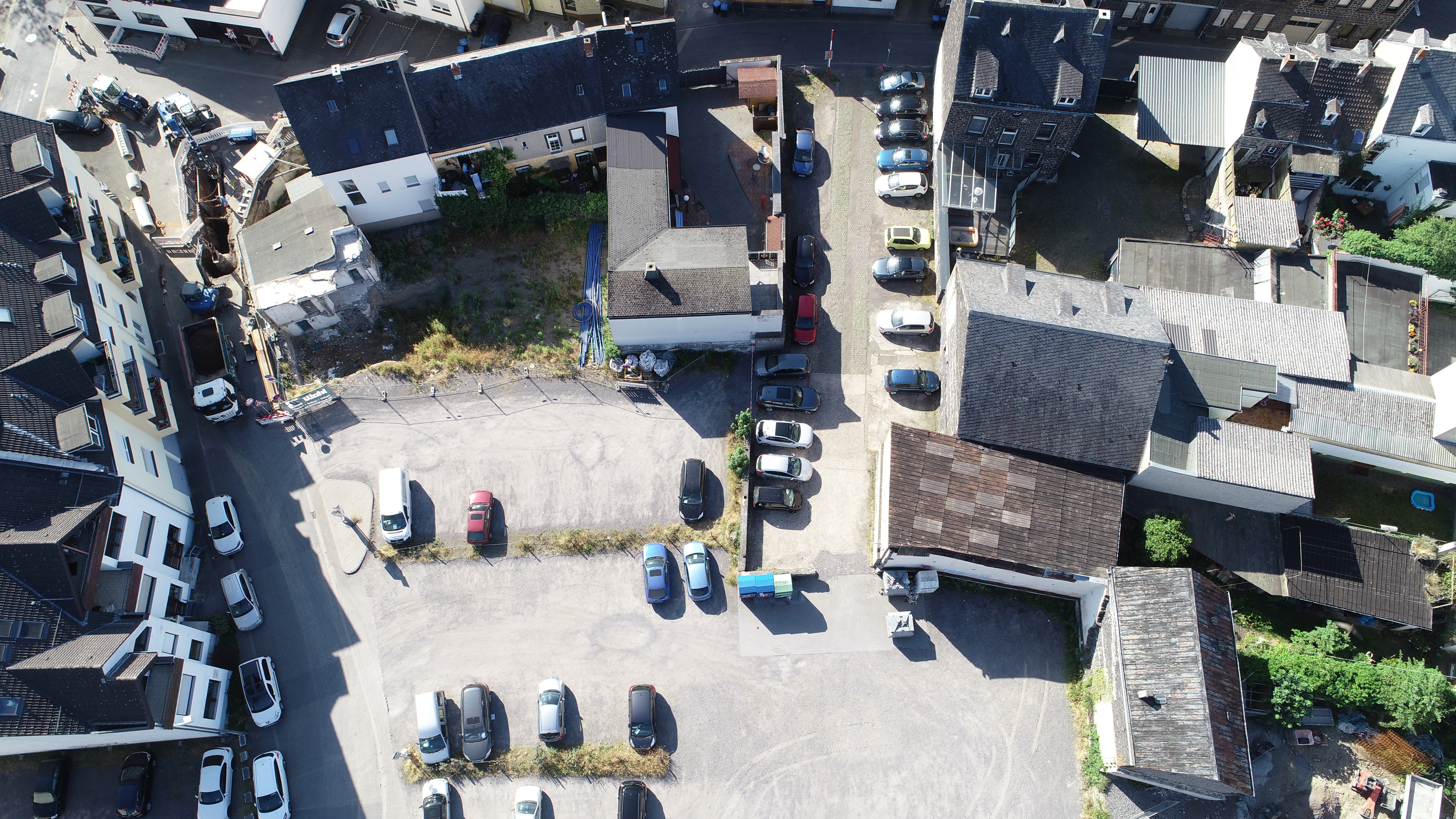 Eine Aufnahme von oben - man sieht einen Parkplatz mit Autos, Innenhöfe und Dächer von Häusern