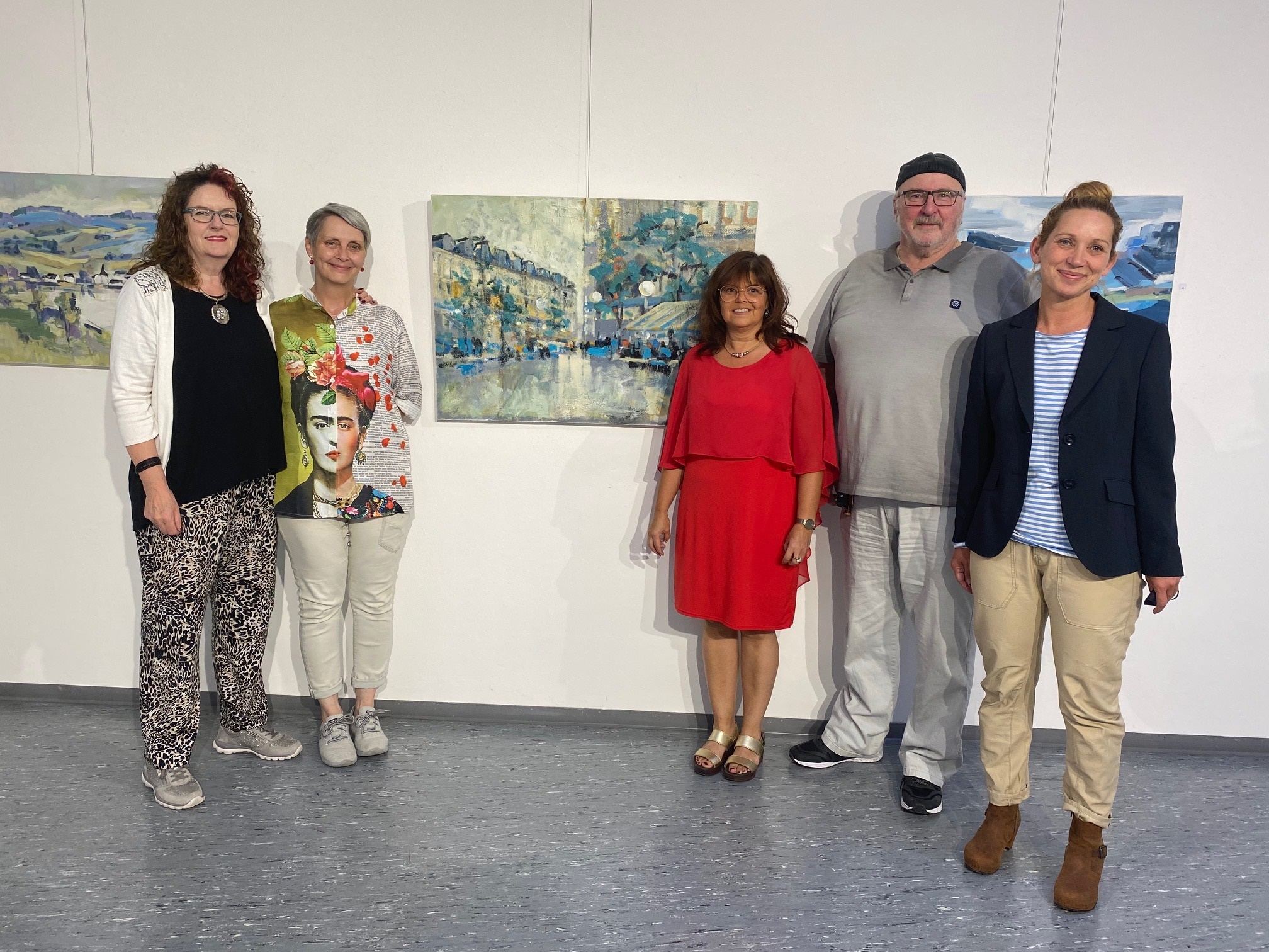 Vier Frauen und ein Mann stehe vor einer Wand mit verschiedenen Gemälden