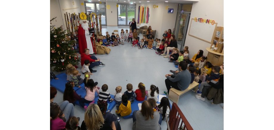 Kinder sitzen in einem Kreis zusammen - der Nikolaus steht dabei