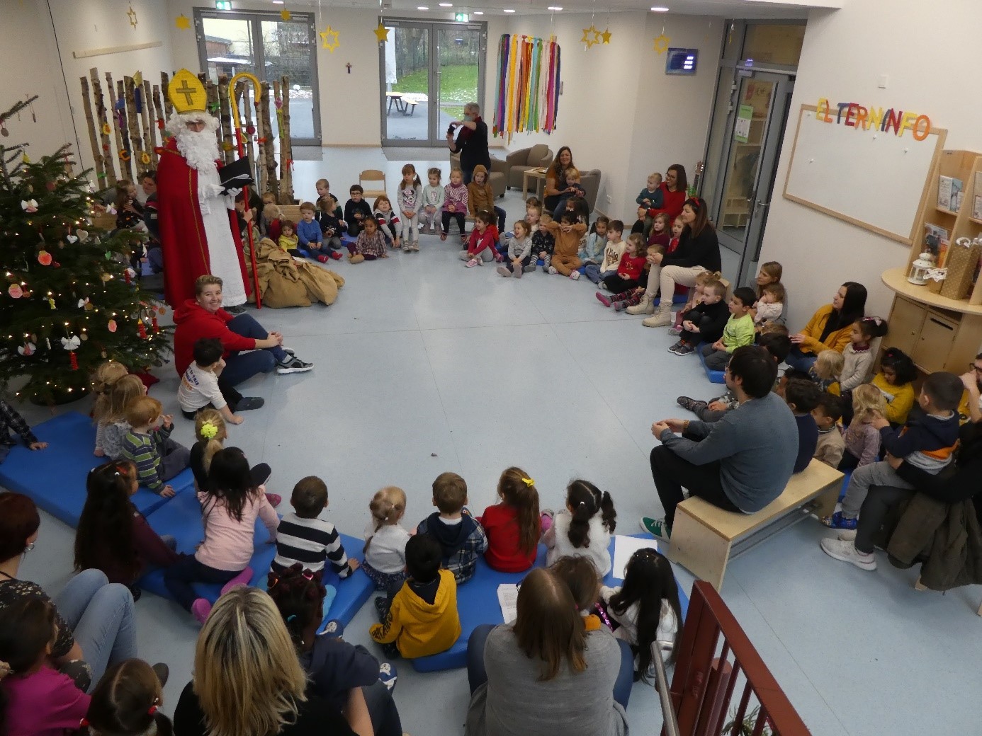 Kinder sitzen in einem Kreis zusammen - der Nikolaus steht dabei
