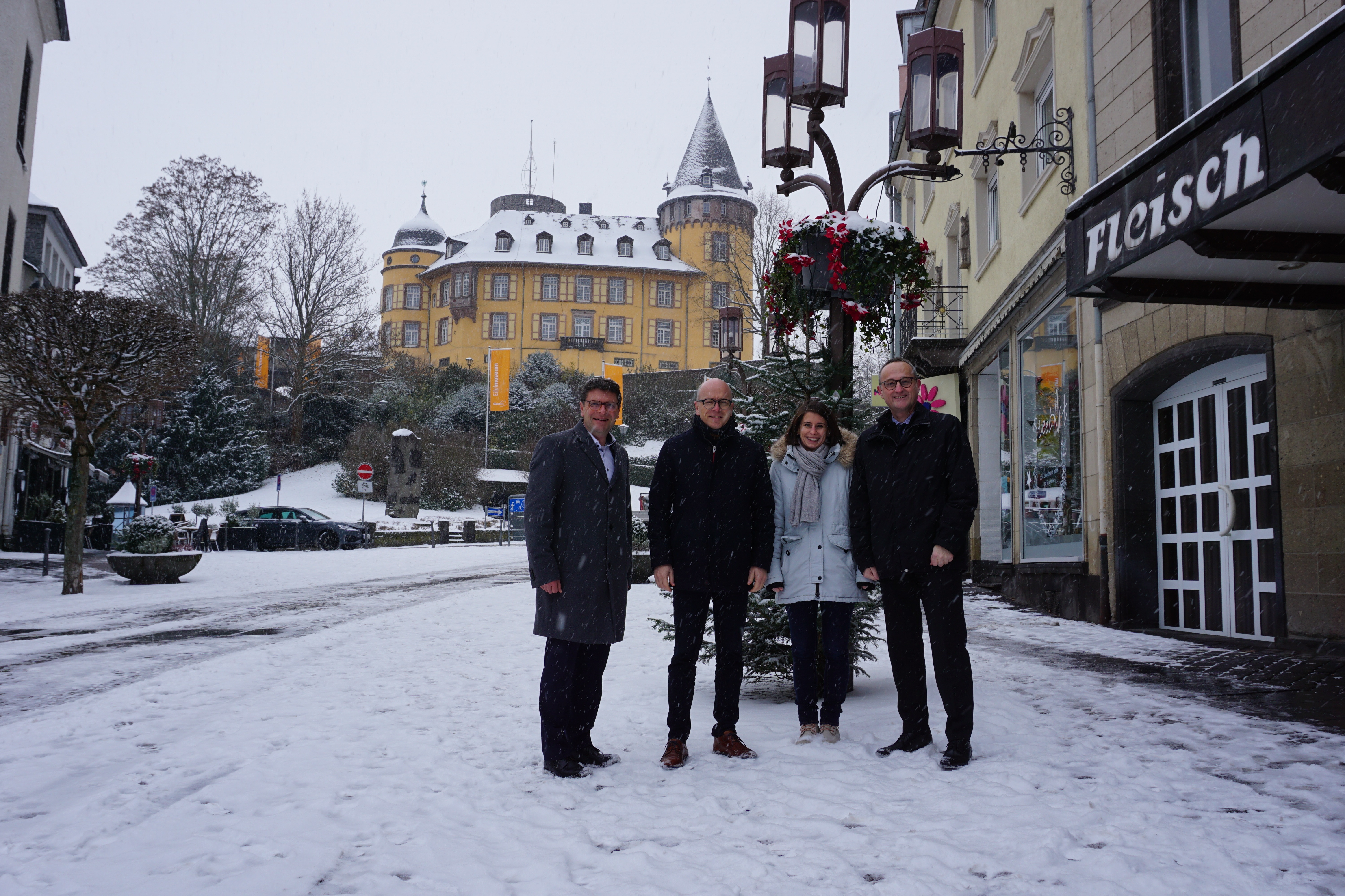 Vier Personen stehen in der Innenstadt vor einer bepflanzen Straßenlaterne.