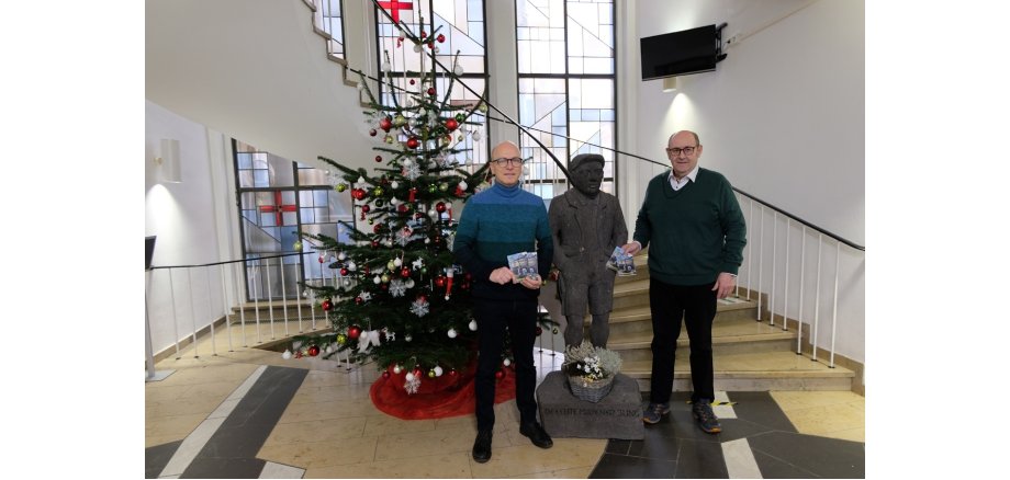 2 Personen mit Plänen in der Hand vor dem Weihnachtsbaum im Eingangsbereich des Rathauses