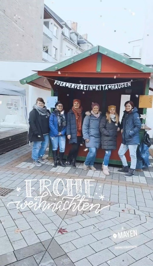 6 Personen stehen an einem Weihnachtsmarktstand