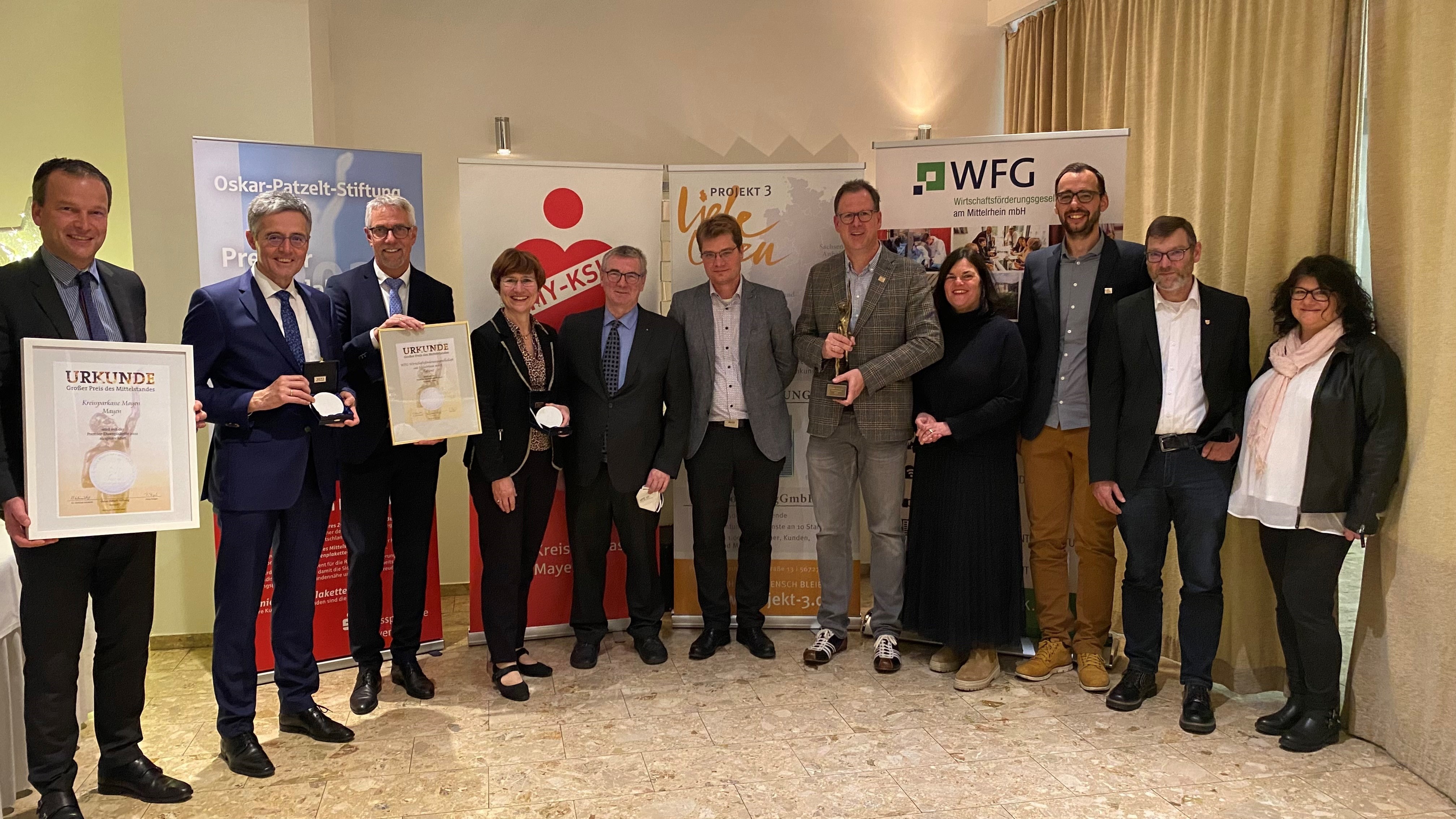 11 Personen stehen zu einem Gruppenbild zusammen, einige davon halten Urkunden in den Händen