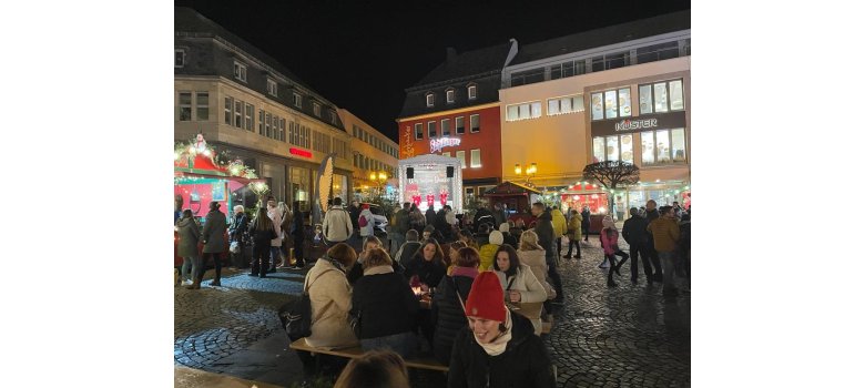 Menschen an Ständen des Weihnachtsmarktes  - es ist dunkel