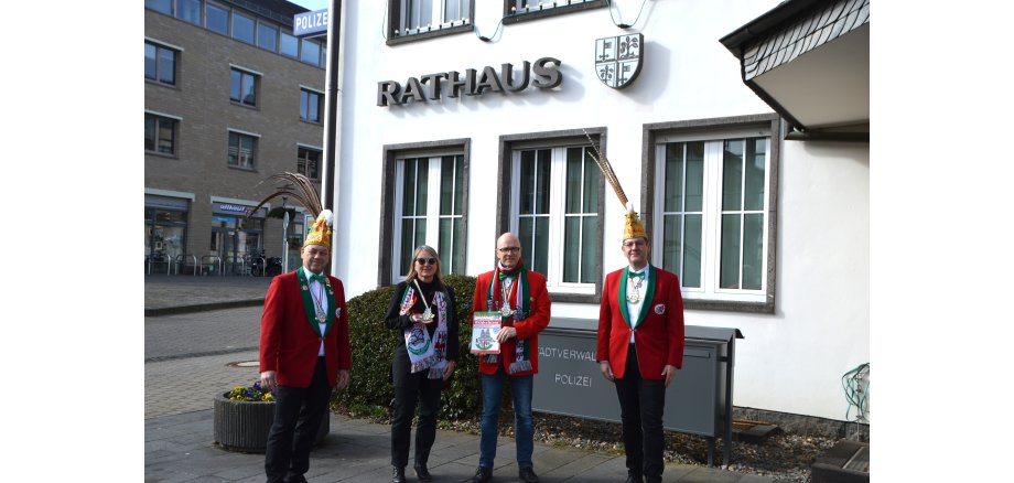 vier Personen stehen in Karnevalistischer Uniform vor dem Mayener Rathaus