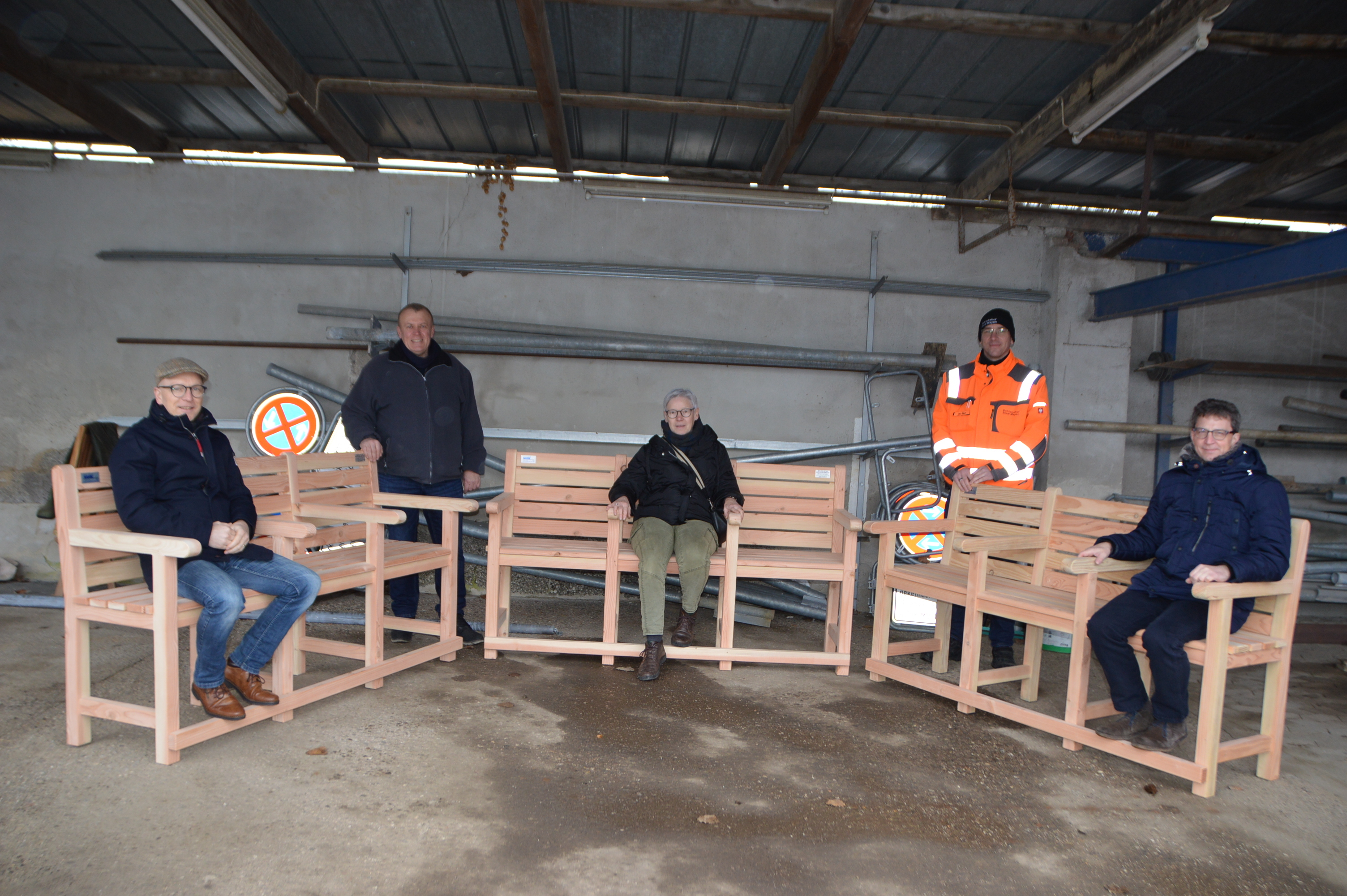 Mehrere Personen sitzen auf 3  Holbänken 