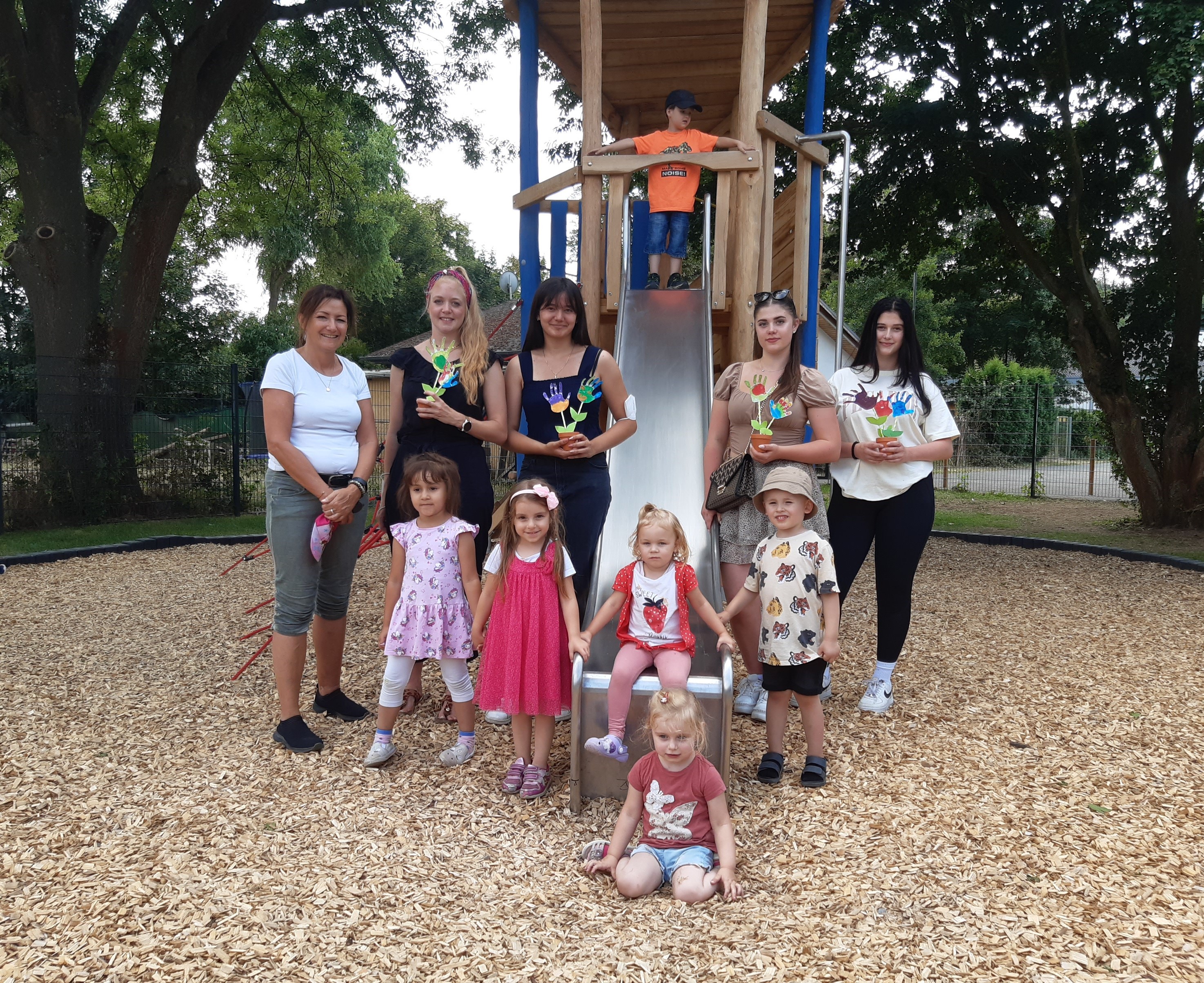 Drei Erwachsene, zwei Jugendliche und fünf Kinder vor einer Rutsche mit Geschenken in den Händen