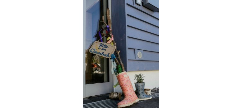 Pflanzen in Gummistiefeln und ein Schild mit "Kita in der Weiersbach