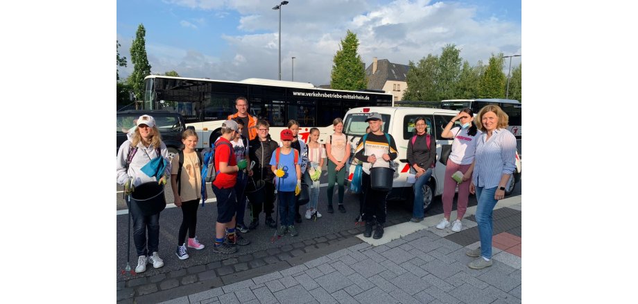 Schülerinnen und Schüler sowie Wolfgang Sauer und eine Lehrerein am Parkplatz vor Bussen und Autos. Alle sind schon entsprechend mit Material ausgestattet. 