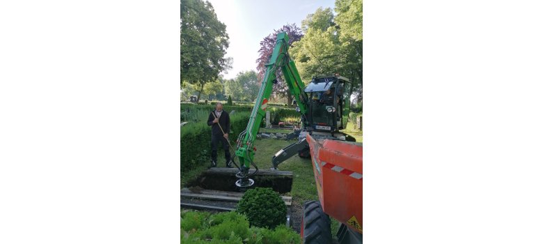 Mitarbeiter des Betriebshofes steht an einem ausgehobenen Grab - daneben ein Bagger