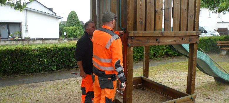 Zwei Personen an einer Rutschbahn auf dem Spielplatz