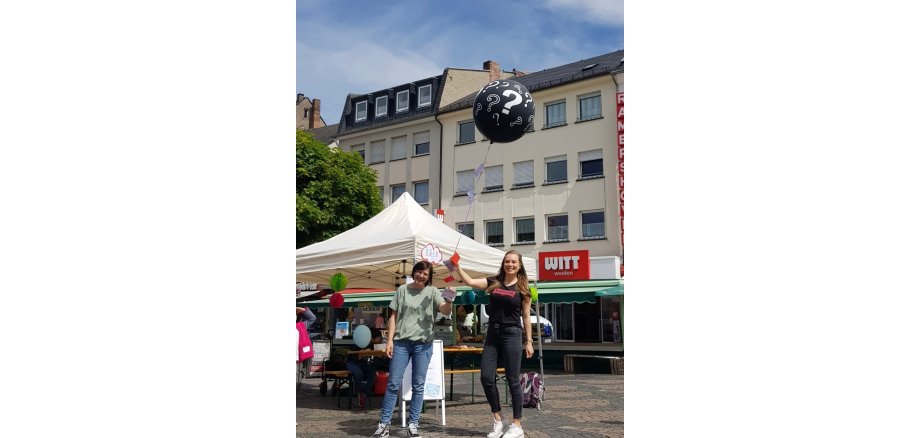 Zwei Frauen lassen auf dem Marktplatz den Wunschballon fliegen