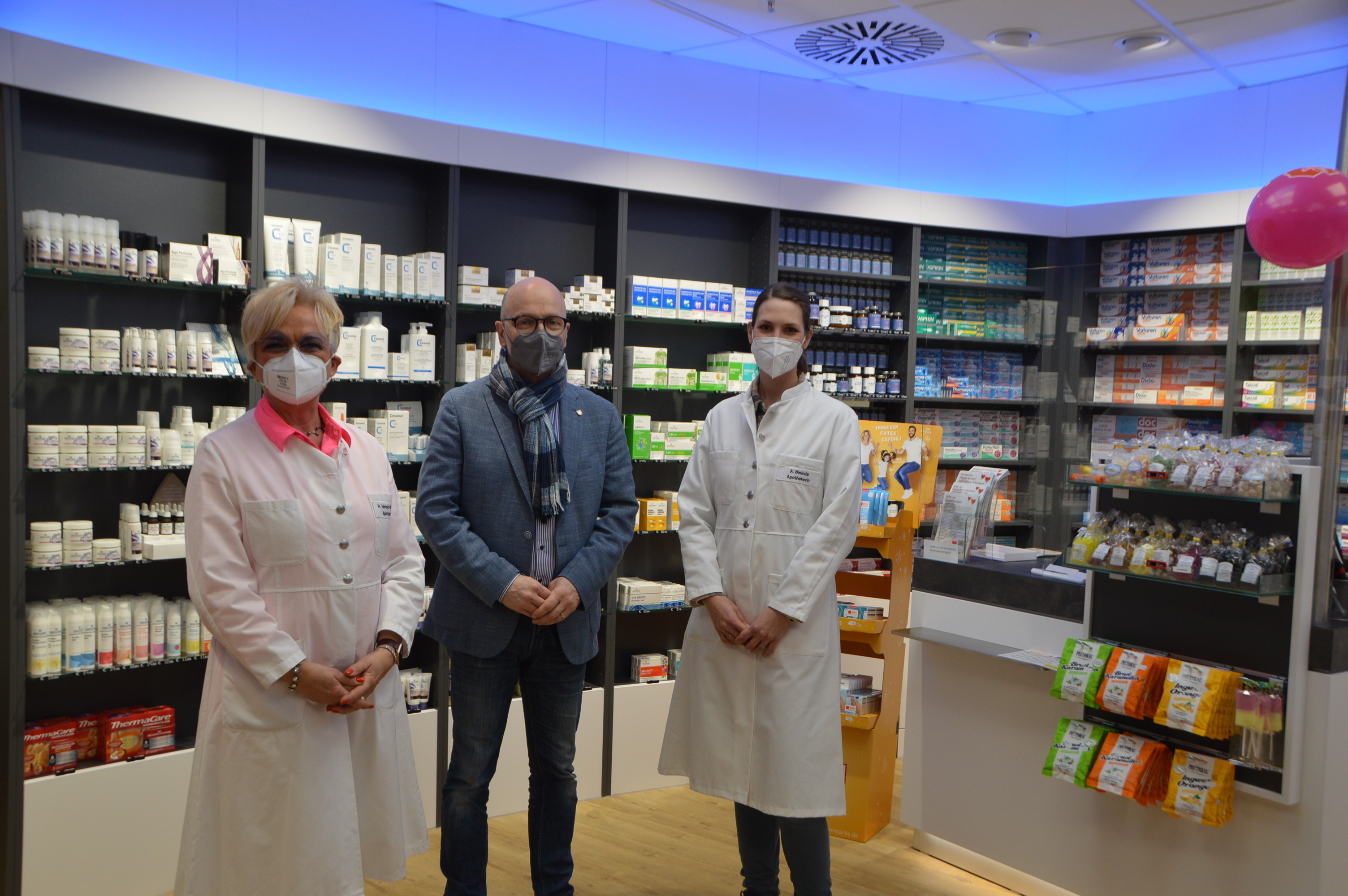 Rita Henrich-Winnen mit Oberbürgermeister Dirk Meid und und Mitarbeiterin Anna Bininda stehen in der neuen Apothekenfiliale nebeneinander und mit Maske