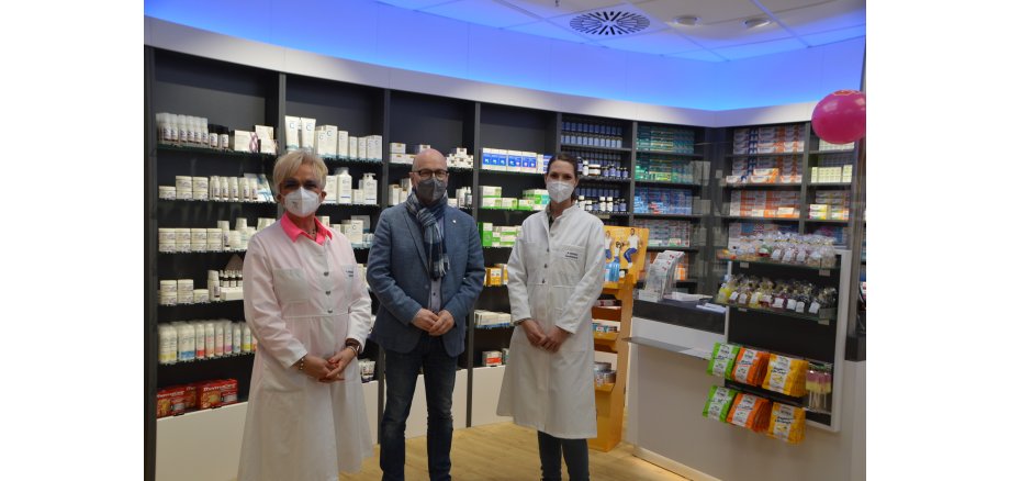 Rita Henrich-Winnen mit Oberbürgermeister Dirk Meid und und Mitarbeiterin Anna Bininda stehen in der neuen Apothekenfiliale nebeneinander und mit Maske